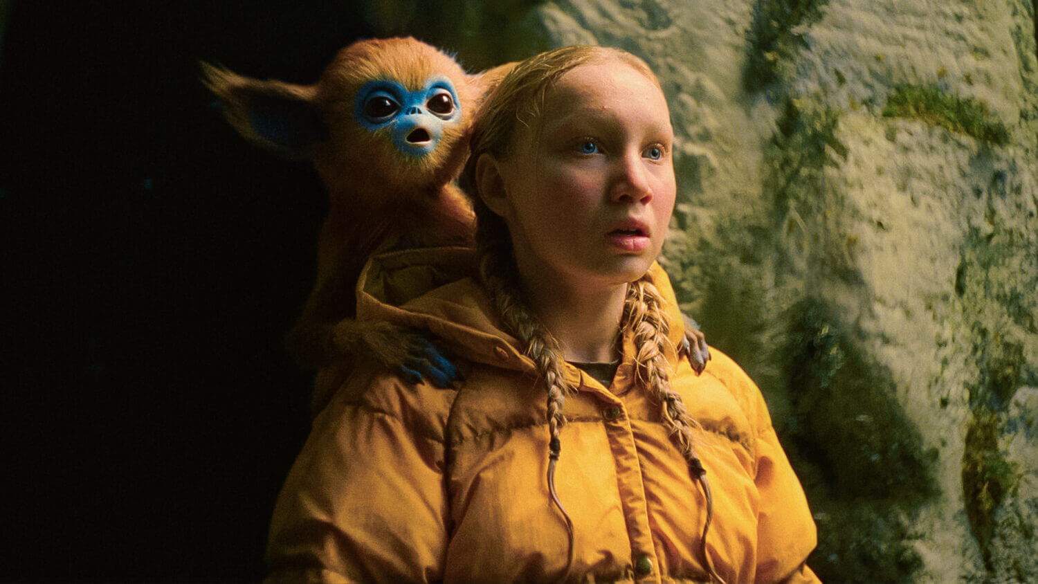 A young girl in a yellow raincoat stares in awe while a small creature sits on her shoulder
