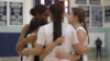 members of a girls' high school basketball team huddle on the court