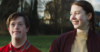 a boy with down syndrome looks forward while a young woman standing beside him looks his way